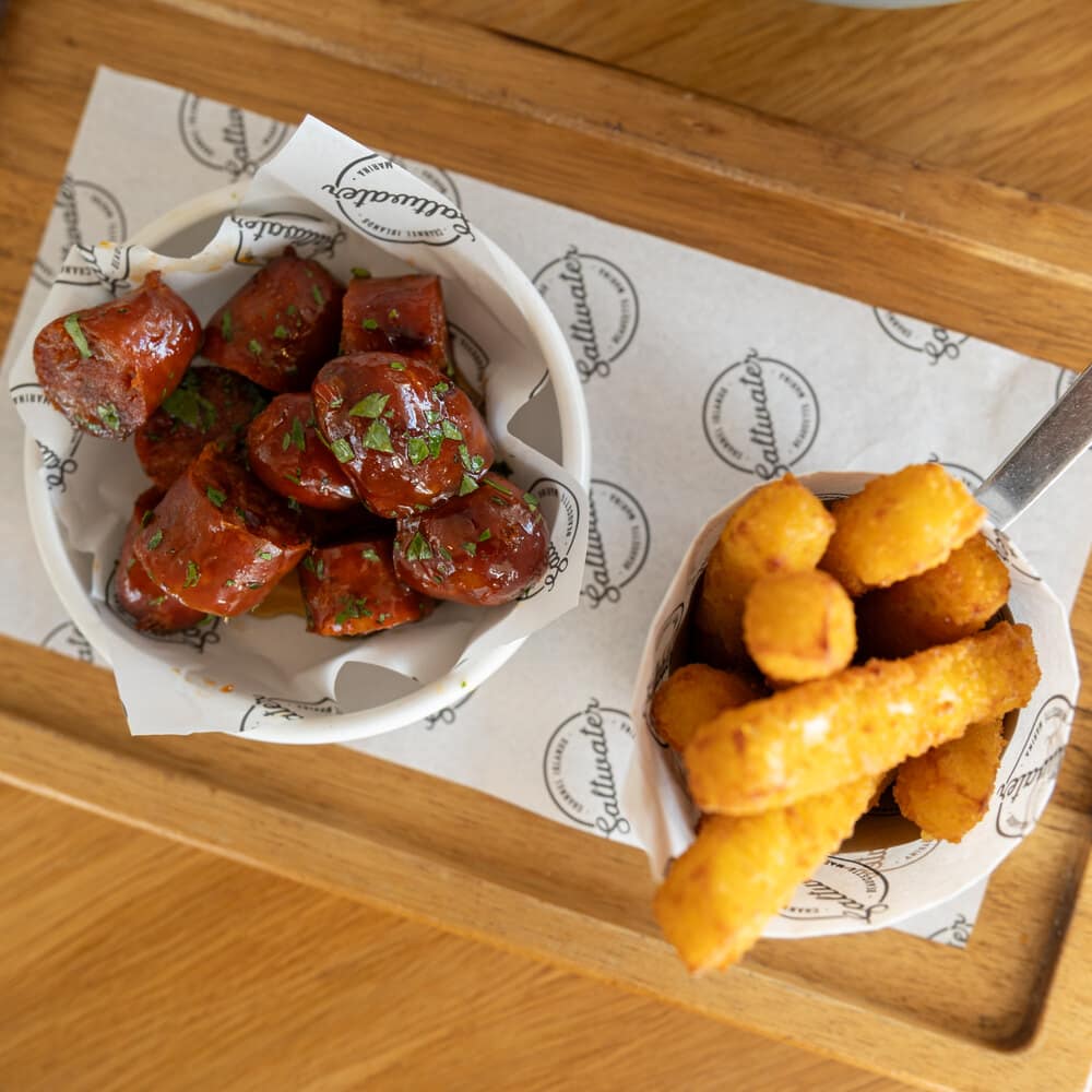 Glazed chorizo and golden croquettes served on a wooden board at Saltwater