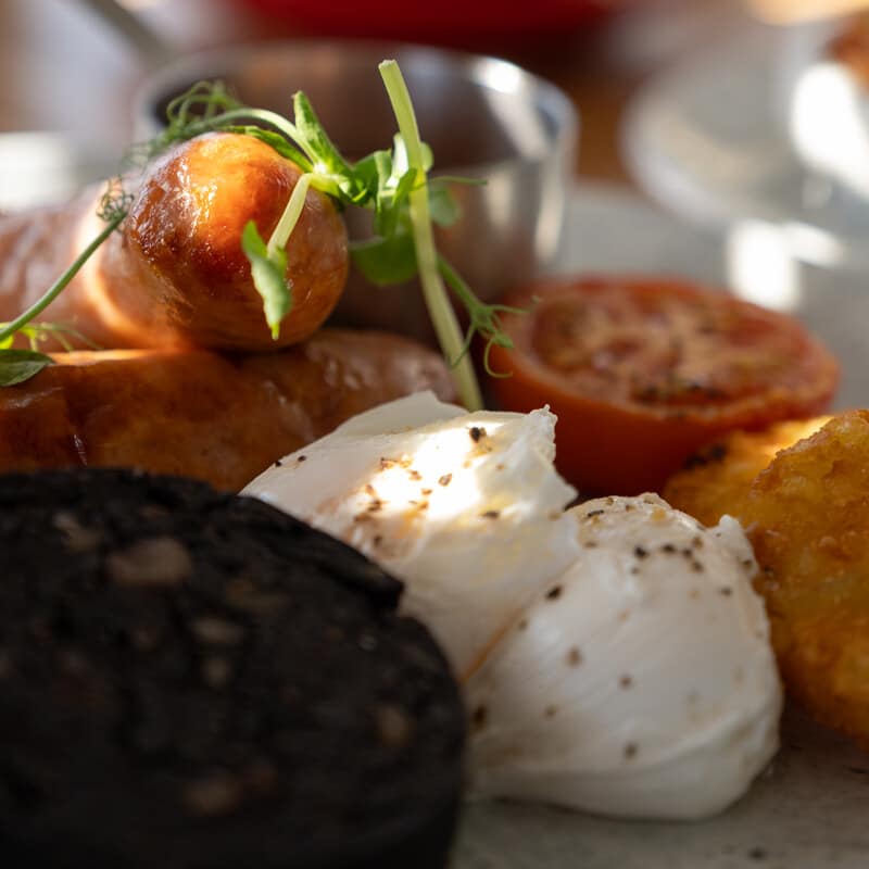 Close-up of a Saltwater breakfast with black pudding, poached egg, roast tomato and hash brown