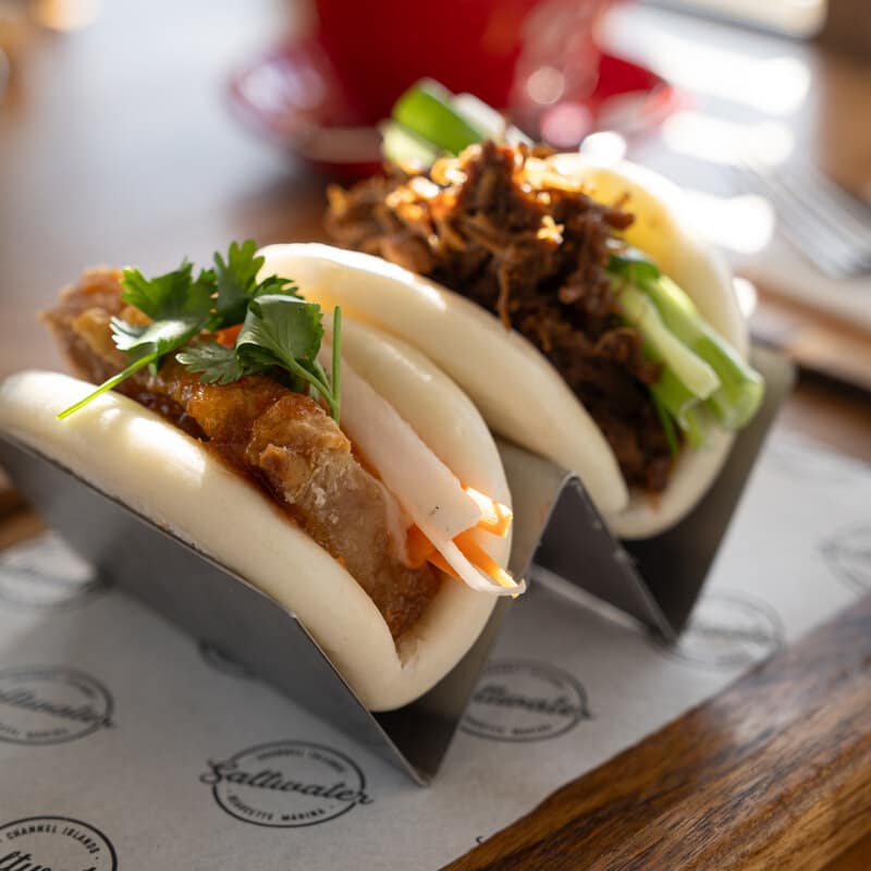 Two filled bao buns served in a stand at Saltwater
